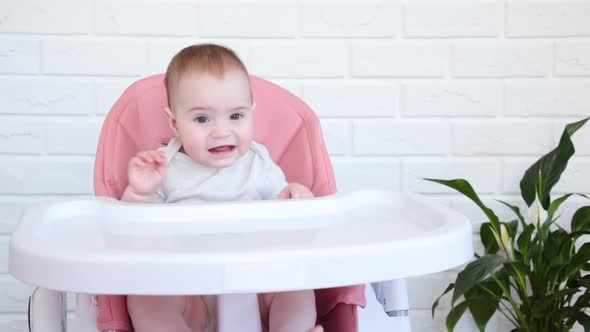 Cheerful little girl sits in child's chair and cry.