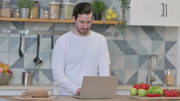 Young Man Working on Laptop in Kitchen