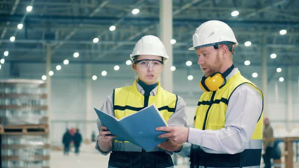 Factory Workers are Looking Through the Report Together