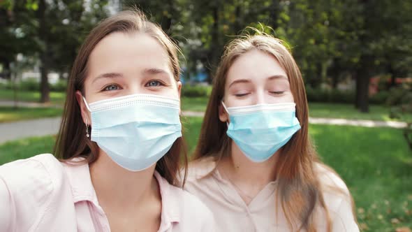 Happy young women students wearing medical face masks talking video calling on chatting.