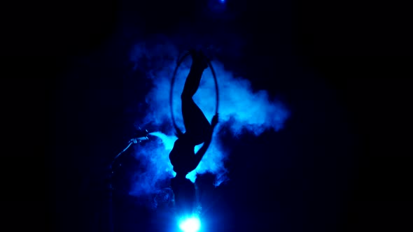 Aerial Acrobat Woman on Circus Stage. Silhouette on a Blue Background.