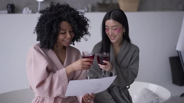 Two Positive Successful Freelancers Clinking Glasses Drinking Juice in Bathroom