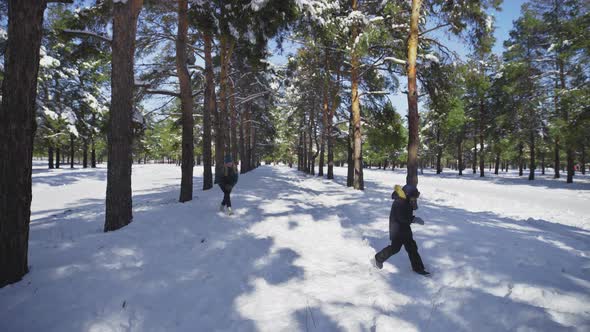 Mother and Son Plays in Snowballs in Winter Park