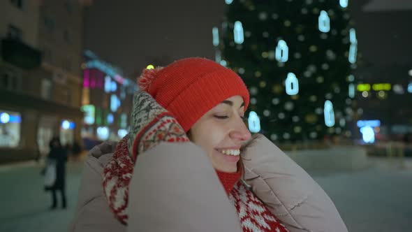 Close Up Portrait of Happy Cheerful Young Woman in Red Cap and Scarf Standing on City Square at