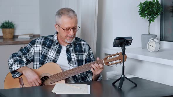 A Middleaged Blogger Plays Guitar While Shooting a Music Video
