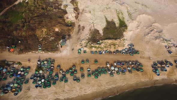 Aerial birdseye dolly right of bunch of coracle boats on seashore in La gi, Vietnam