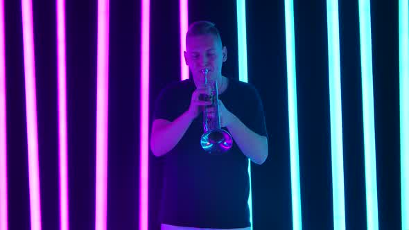 A Man Plays the Trumpet in the Studio Against a Background of Pink and Blue Neon Tubes