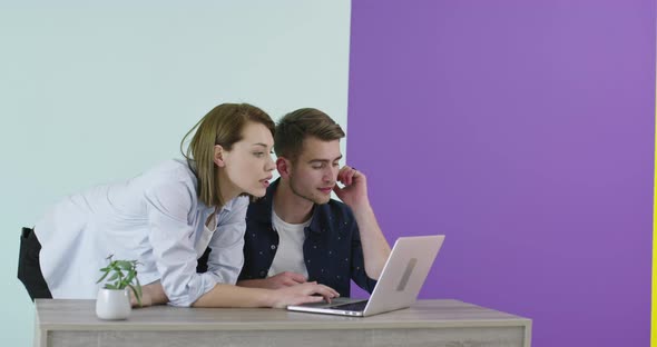 Positive Smiling Man and Woman Near Working Place with Laptop Cooperating in Office