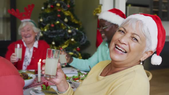 Happy mixed race senior woman celebrating meal with friends at christmas time