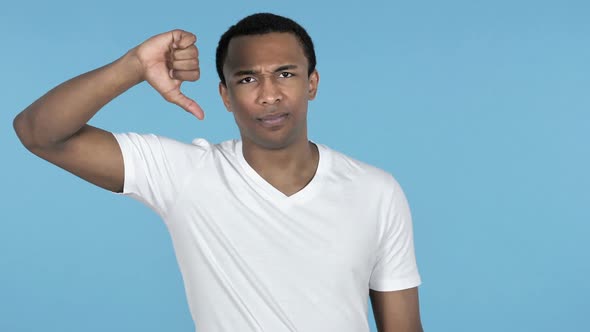 African Man Gesturing Thumbs Down Blue Background