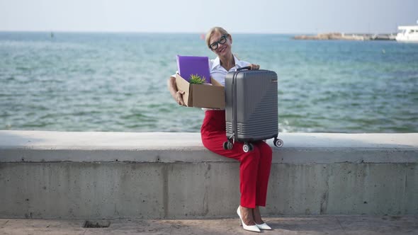 Wide Shot of Happy Gorgeous Woman Smiling Looking at Camera Sitting on Mediterranean Sea Embankment