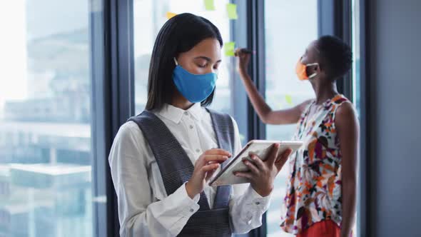 Portrait of asian woman wearing face mask using digital tablet at modern office