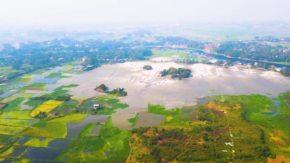 Aerial landscape view of rural village with cultivated wetland and small river, zoom in shot