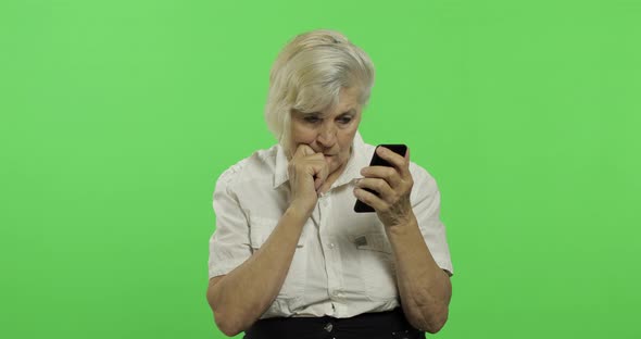 An Elderly Woman Works on a Smartphone. Old Grandmother Smiles. Chroma Key