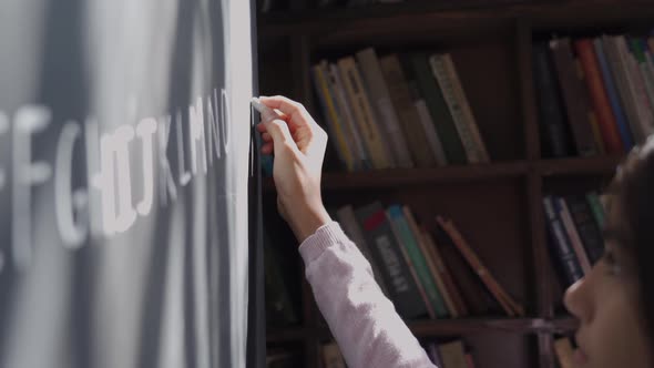 Indian School Girl Pupil Holding Chalk Writing English Letters on Blackboard