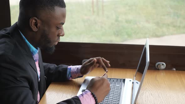 Black Man Makes Payment Bank Card on Laptop Buys Online Shopping Sits in Cafe