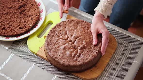 Woman Slicing Crust of Caramel Chocolate Cake on Wooden Cutting Board