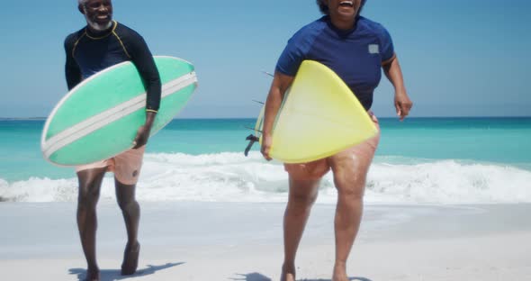 Senior couple running with surfboards