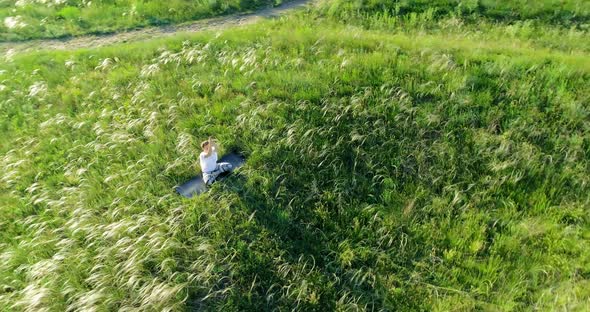 Girl meditates sitting on a beautiful green meadow