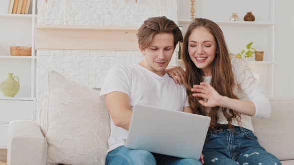 Happy Caucasian Millennial Couple Husband and Wife Making Video Call Remotely From Home on Couch
