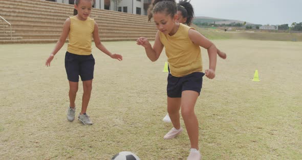 Video of happy diverse girls playing soccer in front of school