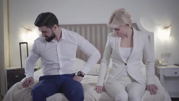 Portrait of Positive Young Caucasian Couple Looking Around in Hotel Room and Falling Back at Soft