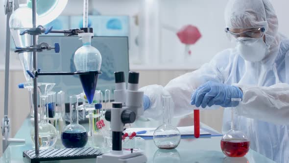 Concentrated Researcher Taking Samples From a Red Liquid