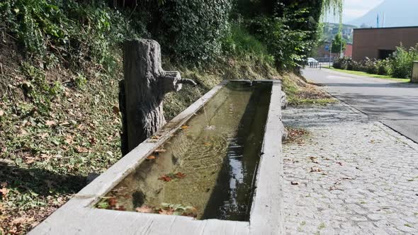 Mountain Water Pours From a Tap Into a Wooden Container on Liechtenstein Street