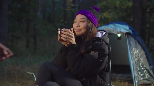 Male Hand Giving Travel Cup To Hiker Woman at Dusk