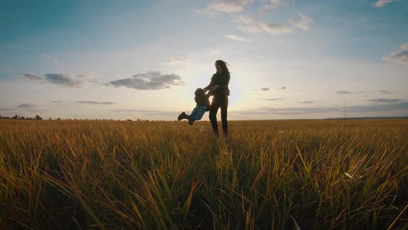 Silhouettes Happy Young Mother and Son Who Play Outdoors at Sunset. Concept of Motherhood