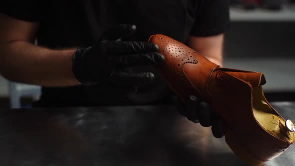 Closeup of Shoemaker in Black Gloves Rubbing Paint on Toe Cup of Brown Leather Shoes with Fingers