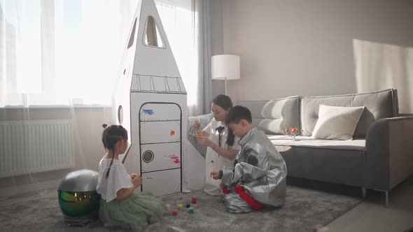 An Asian Female with Kids Play in the Living Room at Home a Boy in an Astronaut Costume Sitting on