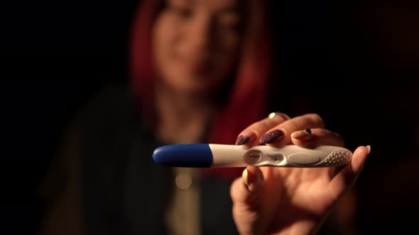 Woman Holds a Positive Pregnancy Test and Smiles