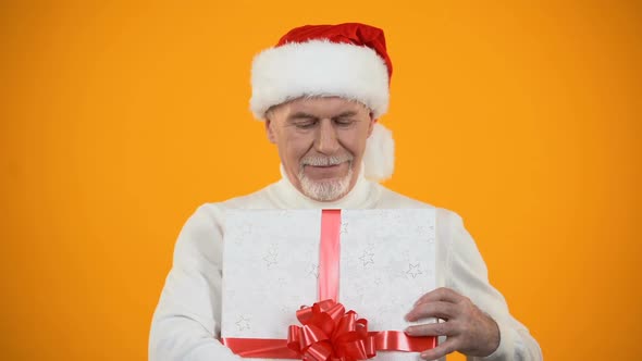 Pleased Senior Male in Santa Hat Hugging Giftbox, Rejoicing New Years Surprise