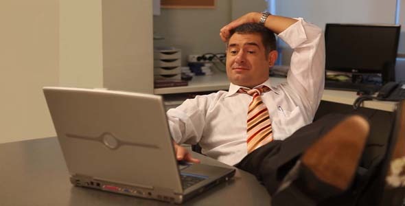 Relaxed Businessman Using Laptop In Office