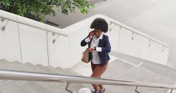 African american businesswoman walking and talking on smartphone