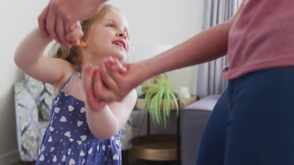 Caucasian mother and daughter having fun dancing in living room