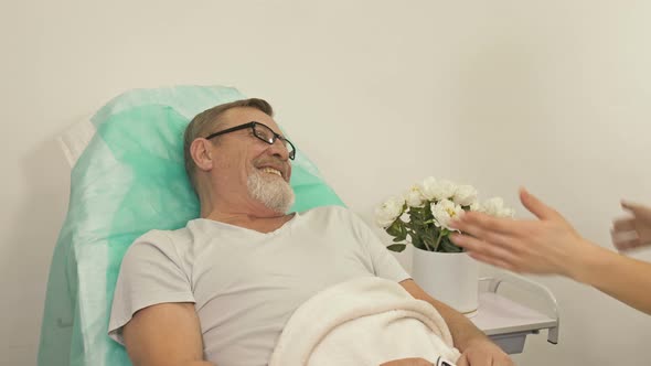 An Adult Daughter Visits an Elderly Father in a Hospital Room