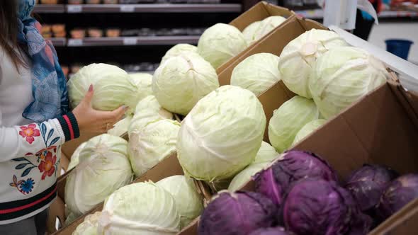 Woman Choosing Cabbage in a Grocery Store