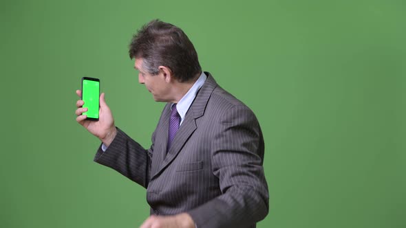 Mature Handsome Businessman Against Green Background