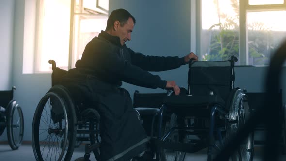 Side View of One American Male Workers in a Workshop at a Factory Making Wheelchairs Sitting at a