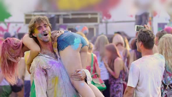 Excited Boyfriend Spanking Girlfriend at Color Festival, Young People Having Fun