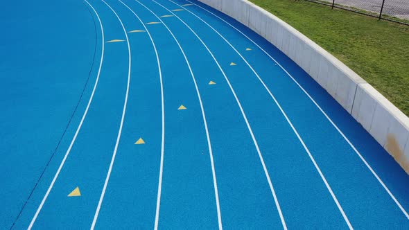 a low angle dolly in, shot over a blue running track. It was taken on a cloudy day with no people in