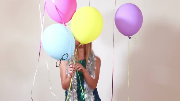 Happy blonde woman jumping with balloons in photo booth