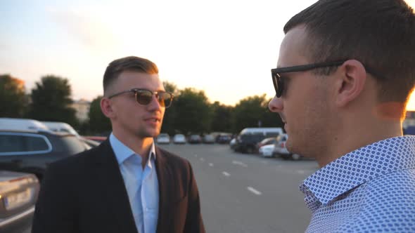 Two Young Business Men Standing Outdoor Near Parking and Talking