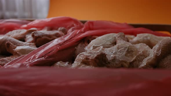 Closeup View of Hands in Gloves Packing Chicken Legs From a Box Into Individual Plastic Bags