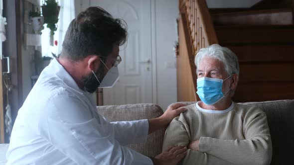 Male professional doctor consulting senior patient during medical care visit wearing masks