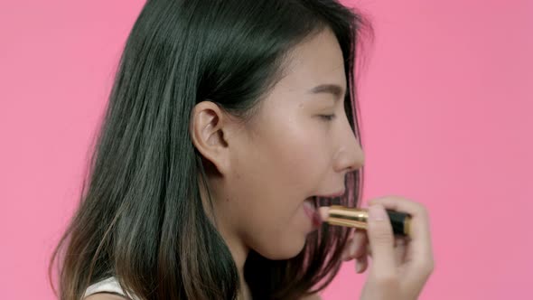 Young beautiful fashionable Asian woman applying lips makeup with cosmetic brush.