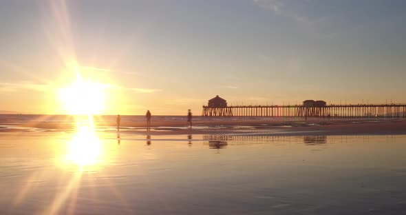 A 4k sunset time-lapse of a family enjoying themselves at the beach low tide with the pier in the ba