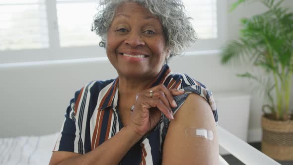 Animation of smiling african american senior woman showing plaster after vaccination